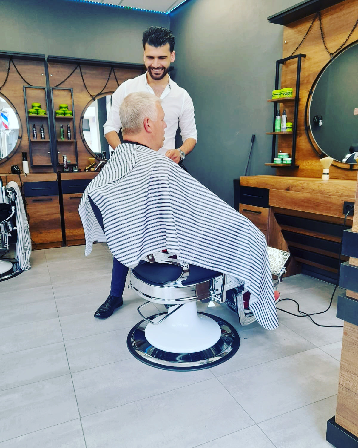 Lachende kapper aan het werk bij een klant in de kappersstoel